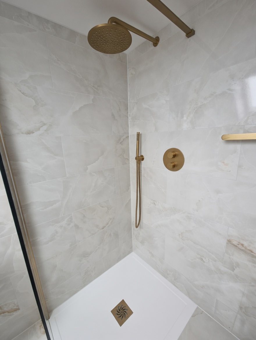 Rainfall shower head and gold controls in marble