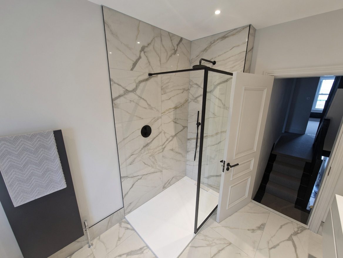 Walk-in shower with black frame and marble walls