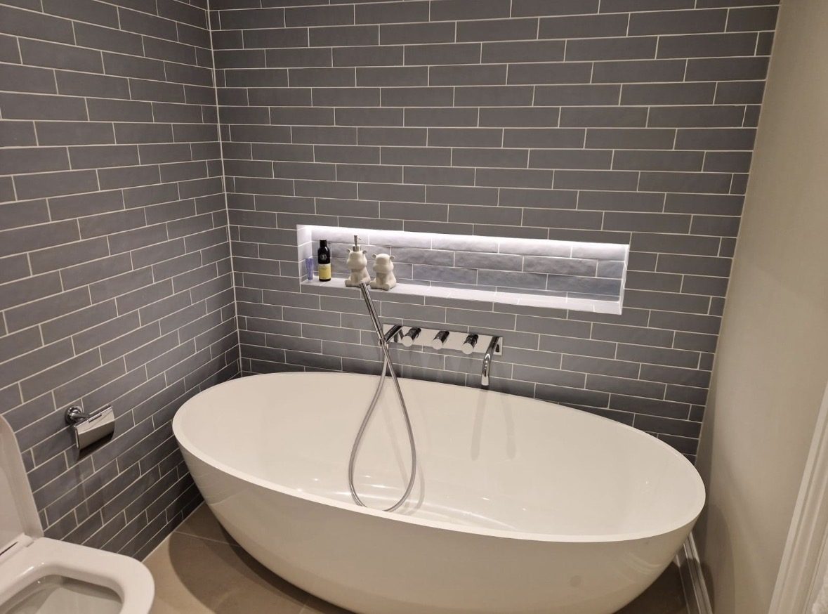 Grey-tiled en-suite with oval freestanding bath