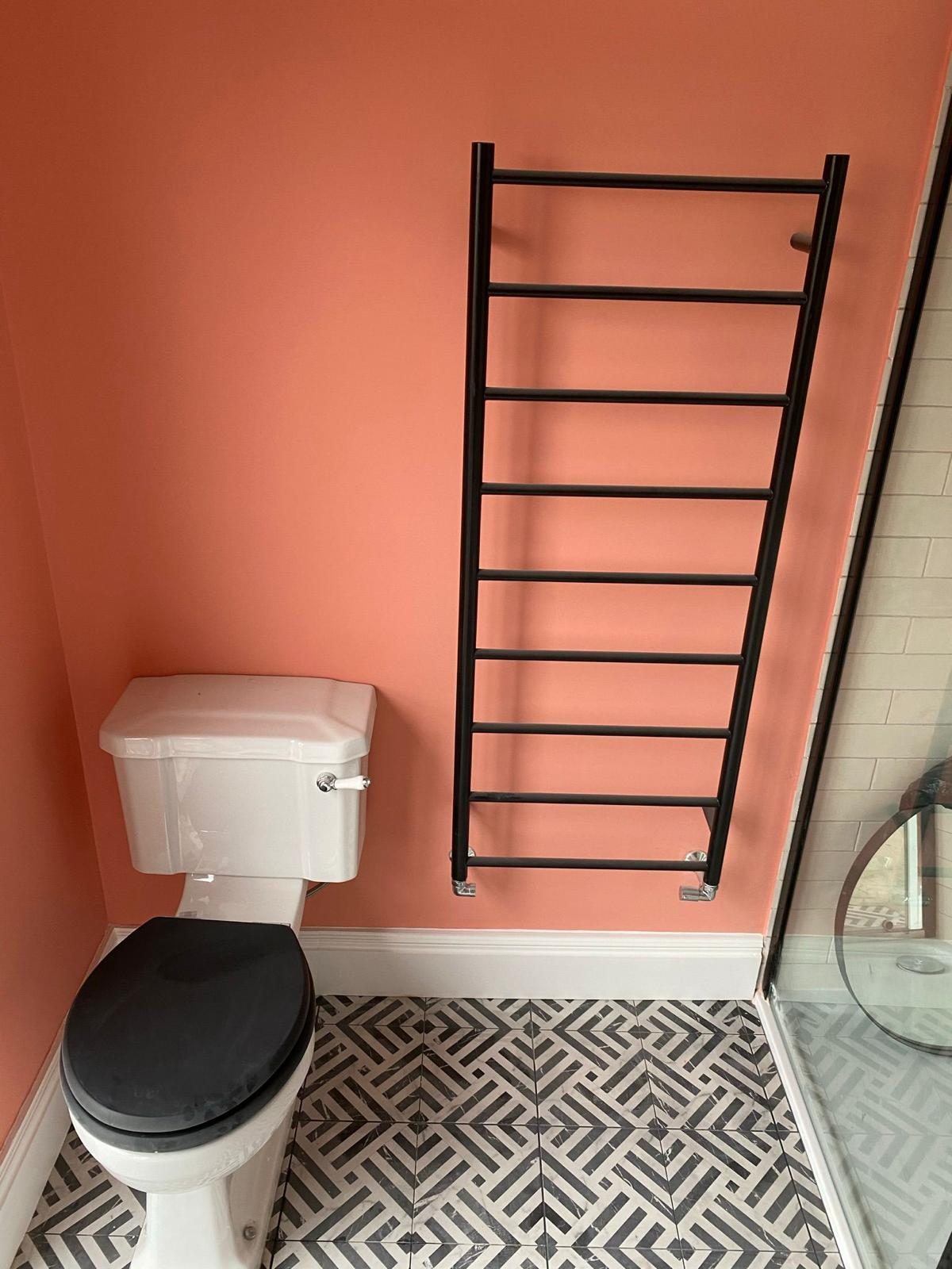 Traditional WC and black ladder towel rail on graphic floor tiles
